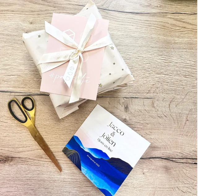 Trouwkaart voor Jacco en Jolien met blauw berglandschap, naast ingepakte cadeaus